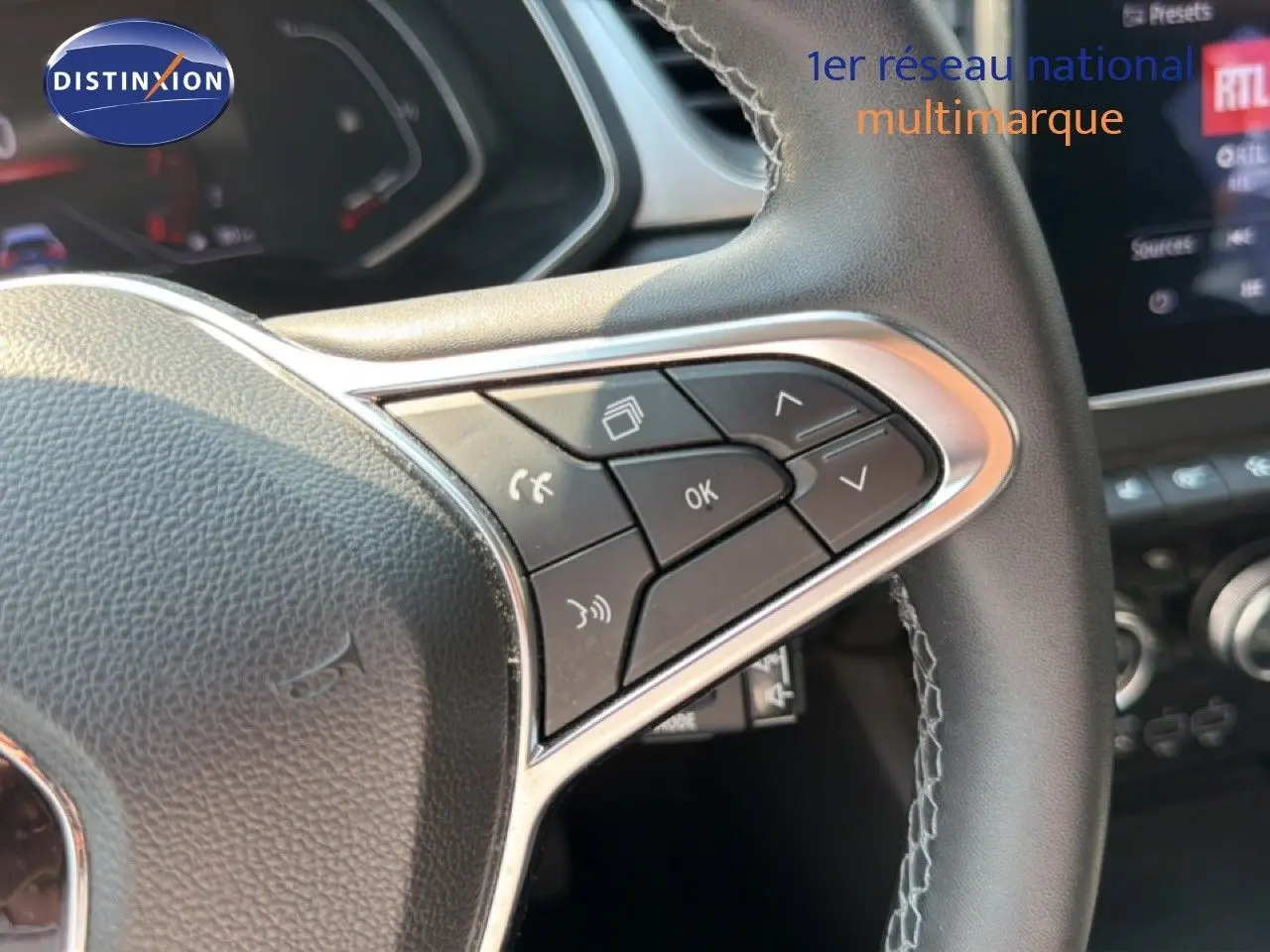Gros plan sur les commandes au volant du Renault Captur 2022, version Intens, avec cuir noir et surpiqûres grises.