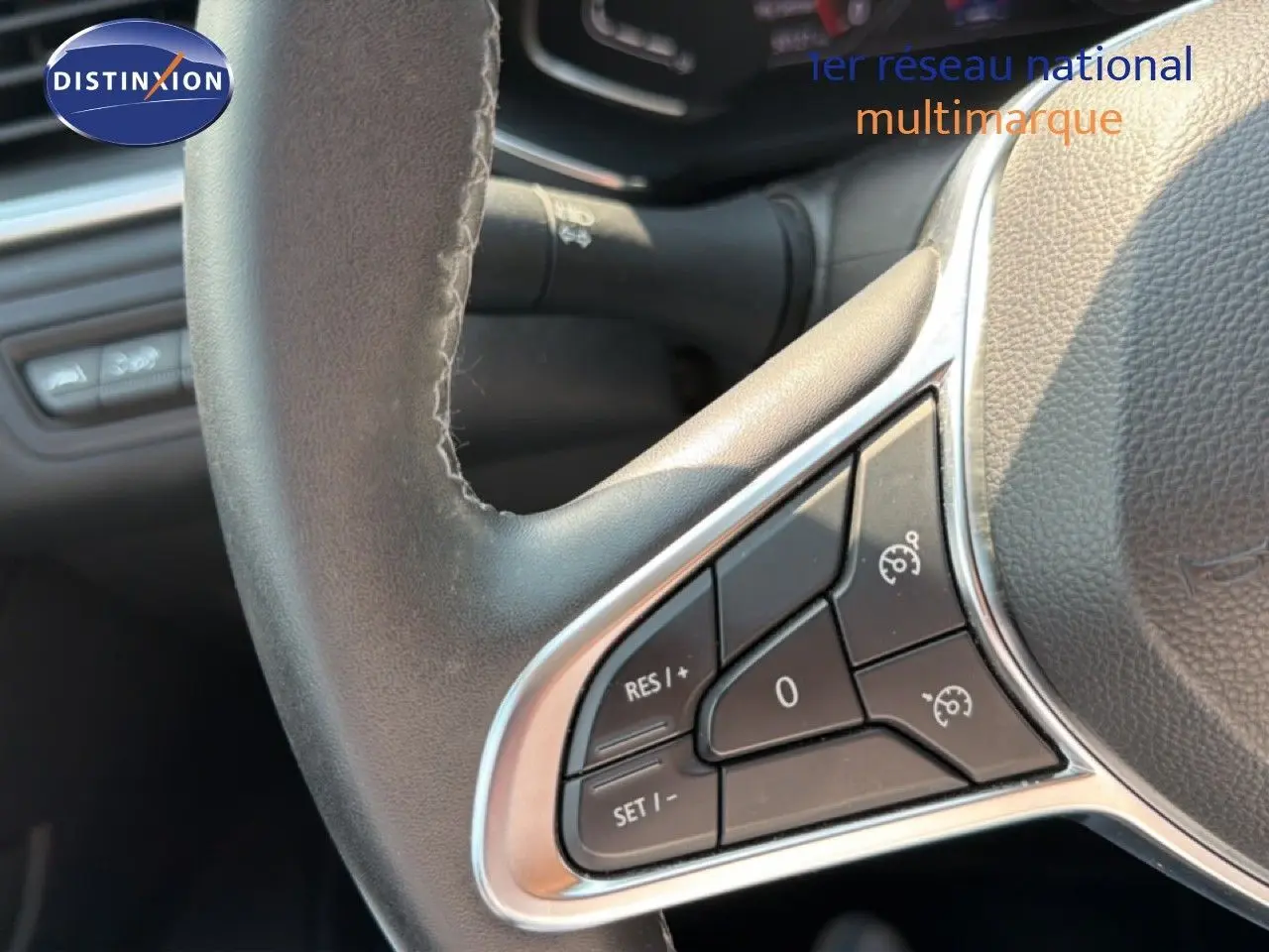 Gros plan sur les commandes au volant du Renault Captur bleu marine fumé, mettant en valeur les boutons de régulateur de vitesse.
