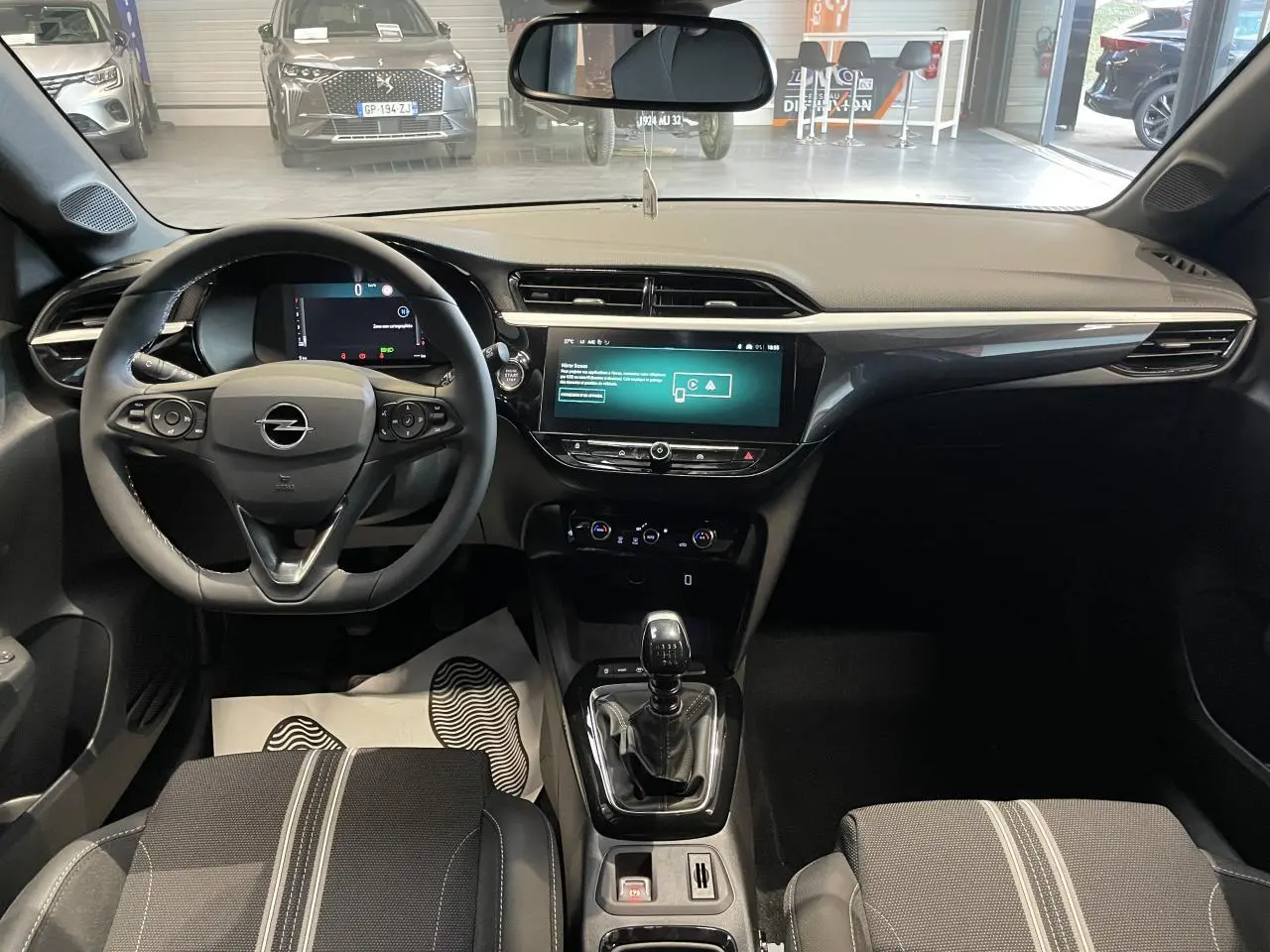 Vue intérieure avant de l’Opel Corsa gris, montrant le volant, écran tactile 10 pouces et levier de vitesses manuel.