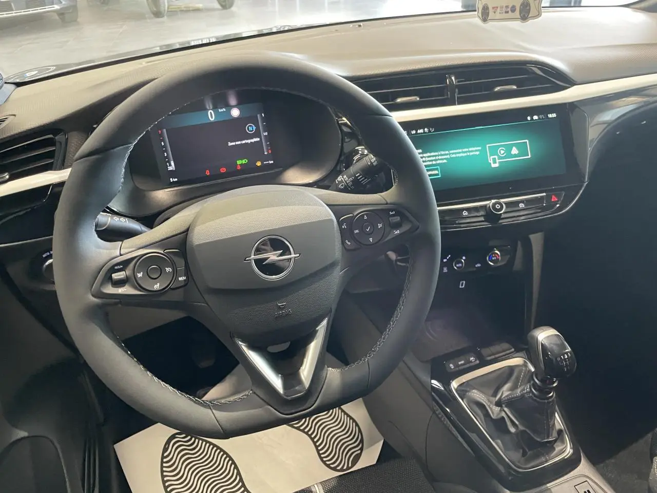 Vue intérieure centrée sur le volant cuir noir et la console avec levier de vitesse manuelle de l'Opel Corsa gris.
