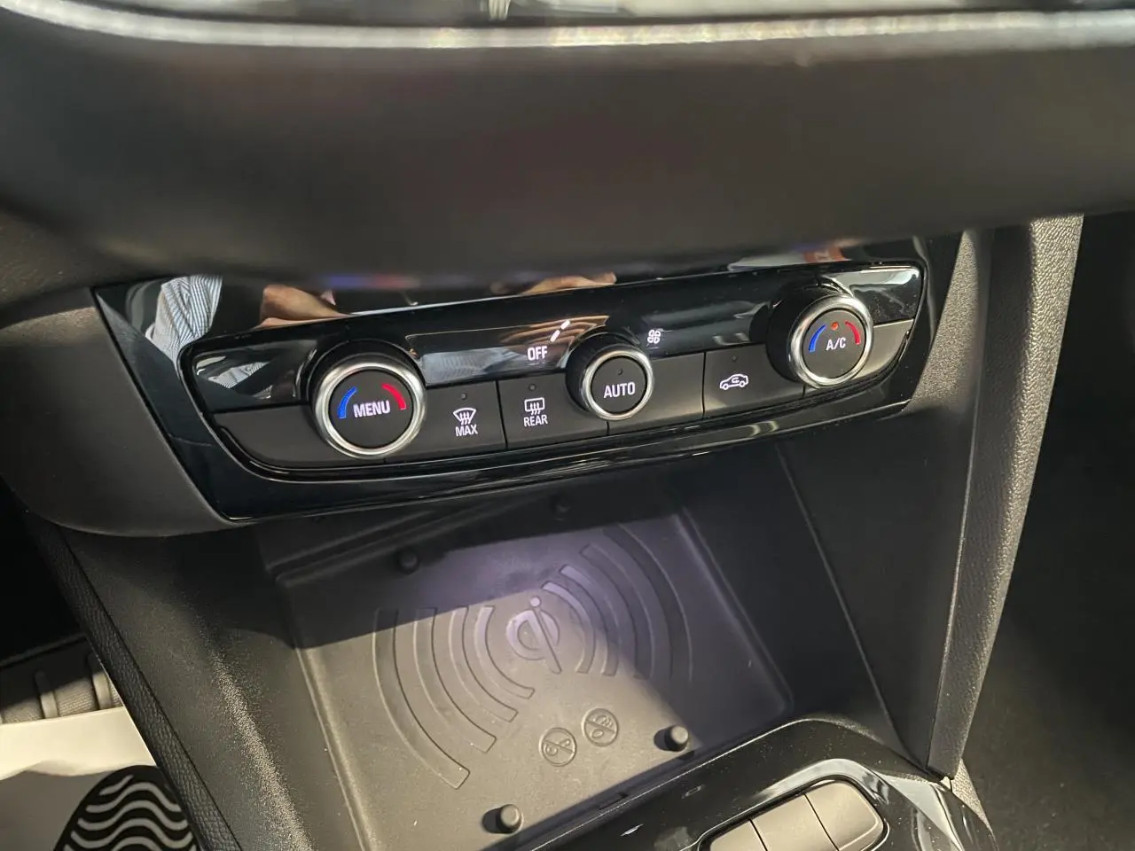 Gros plan sur la console centrale de l'Opel Corsa 2026 avec commandes de climatisation et chargeur à induction noir.