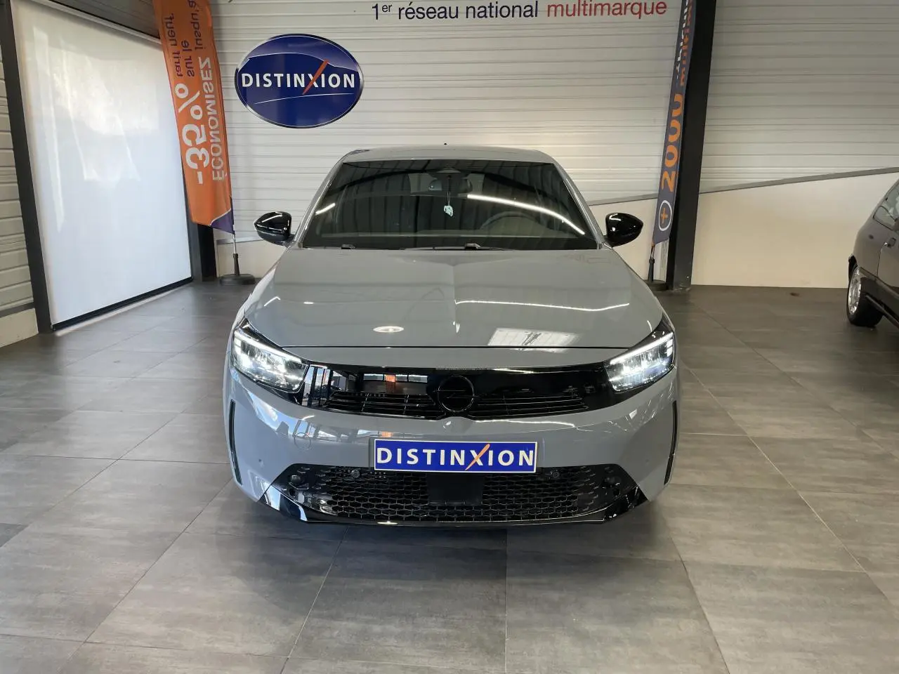 Vue avant d'une Opel Corsa 1.2 Turbo gris avec calandre noire et phares LED allumés en intérieur showroom.