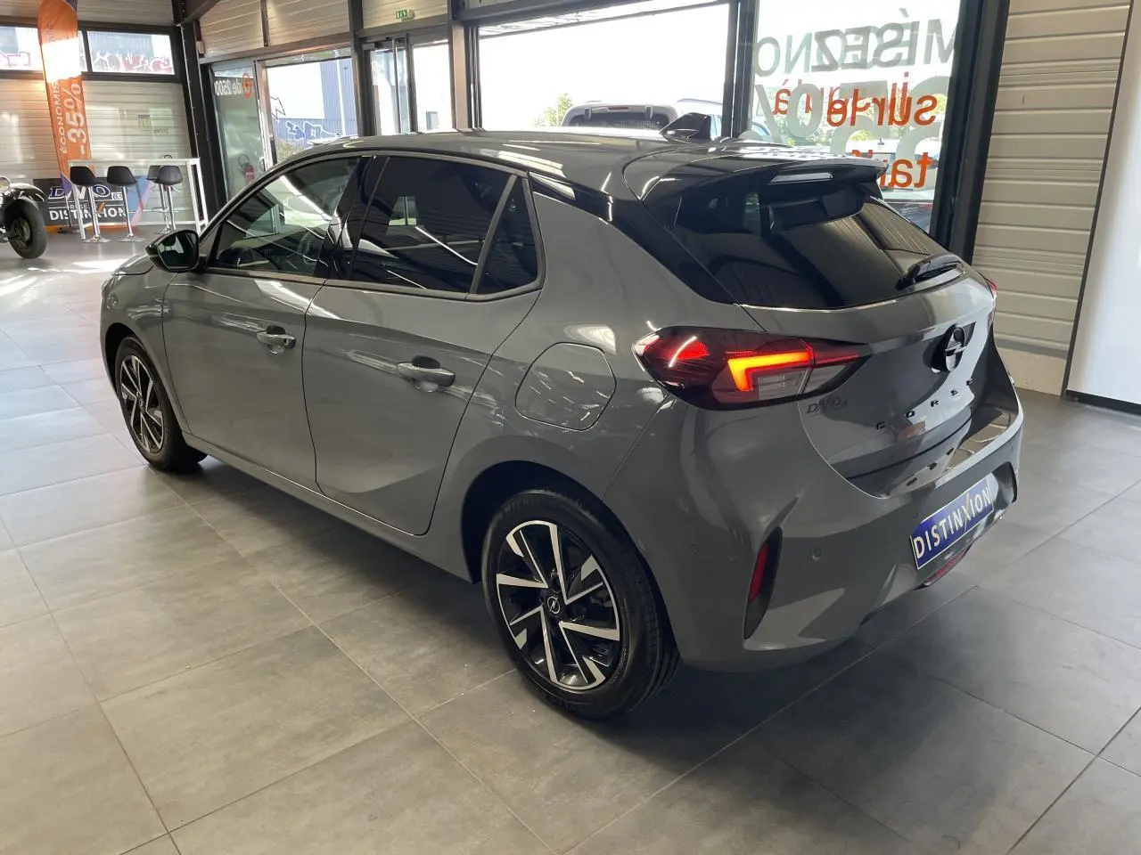 Opel Corsa gris Grafik vue 3/4 arrière droit en intérieur avec jantes alliage et feux LED allumés.