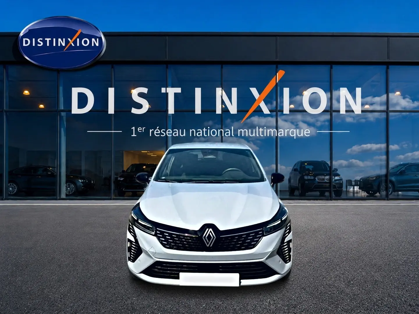 Vue frontale d'une Renault Clio V gris rafale garée devant une vitrine avec logo Distinxion.