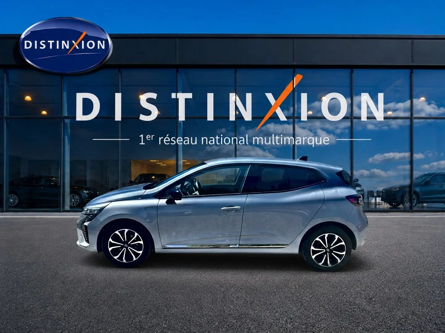 Profil droit d'une Renault Clio V gris rafale, avec jantes alu, devant une vitrine Distinxion.