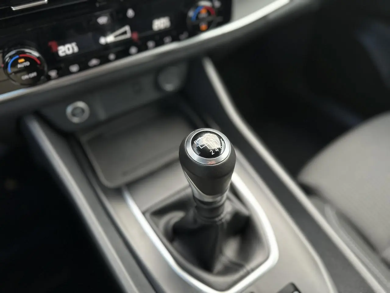 Gros plan sur le levier de vitesses manuel noir du Nissan Qashqai 2024 avec console centrale et commandes climatisation visibles.