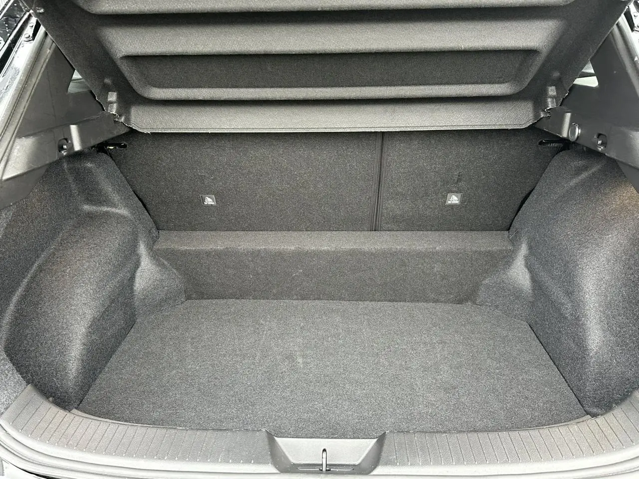 Coffre spacieux et vide du Nissan Qashqai III noir nacré, vue intérieure arrière avec habillage gris foncé.