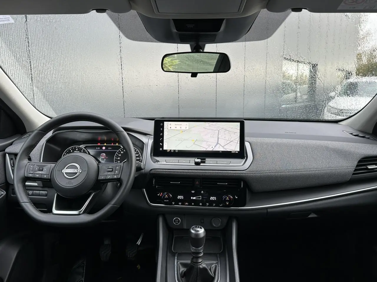 Vue intérieure frontale du tableau de bord noir du Nissan Qashqai 2024 avec écran tactile et boîte manuelle.