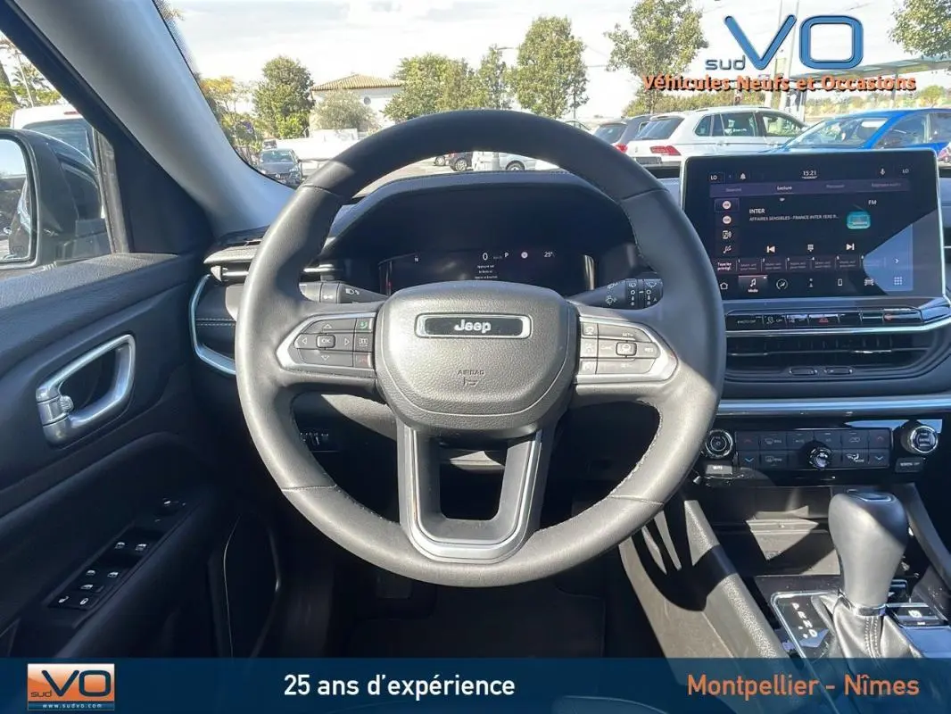 Vue intérieure centrée sur le volant Jeep noir et le tableau de bord avec écran tactile du Compass 2023.
