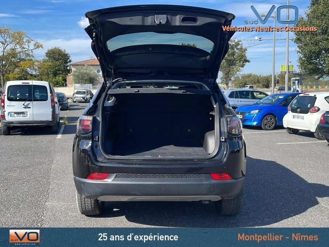 Vue arrière du Jeep Compass noir 2023 avec coffre ouvert, montrant l'espace de chargement vide en extérieur.