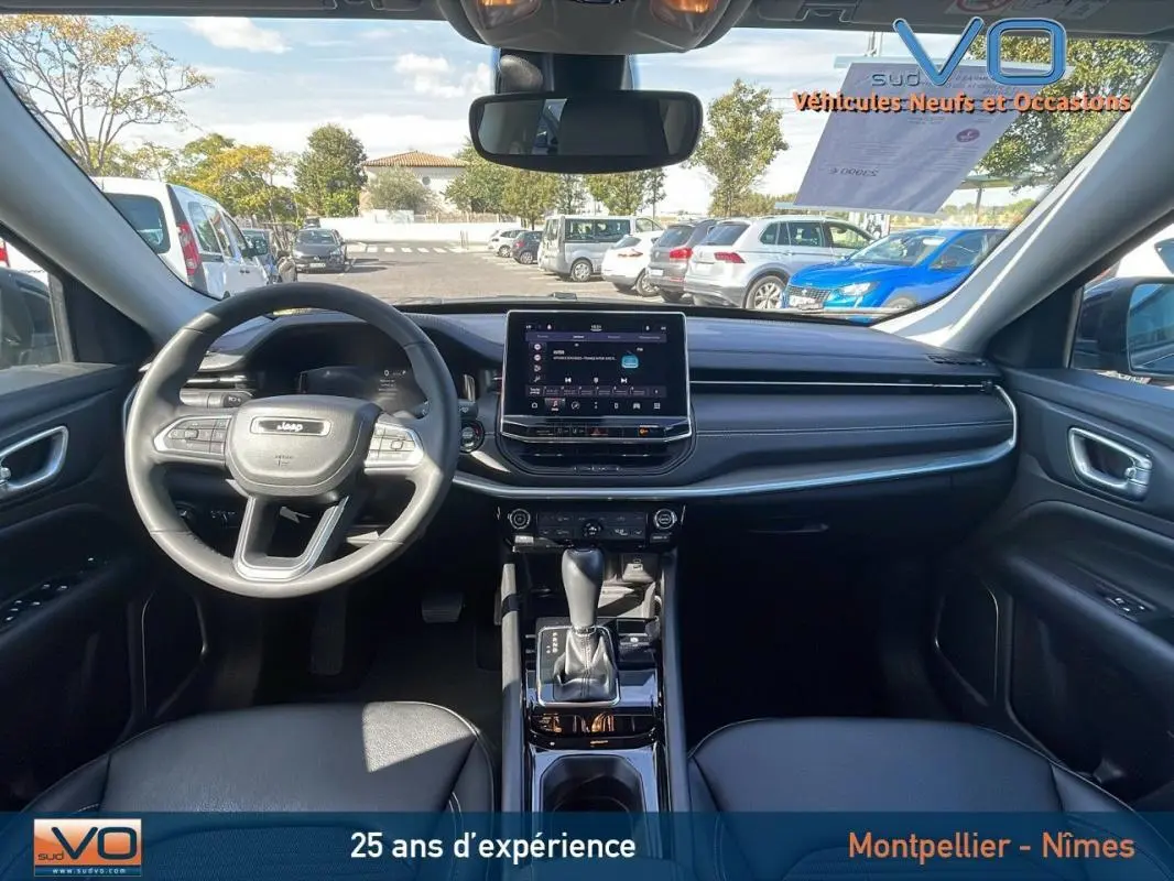 Intérieur du Jeep Compass 2023 noir vu de face, avec écran tactile central et volant multifonction en cuir.