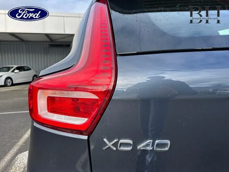 Gros plan sur le feu arrière gauche bleu Denim du Volvo XC40 avec logo du modèle visible sur le hayon.