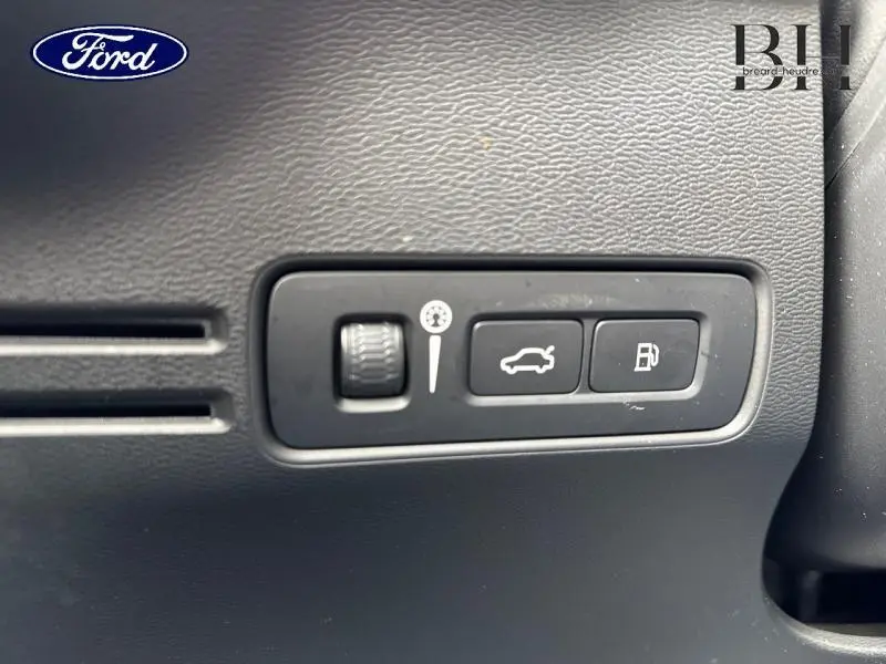 Gros plan sur les commandes intérieures noires du tableau de bord du Volvo XC40 Bleu Denim, boutons ouverture coffre et réservoir.