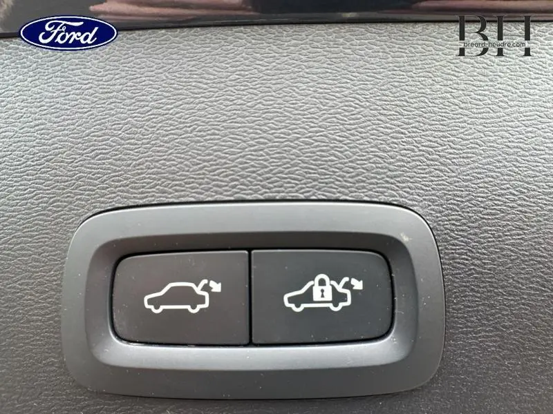 Gros plan sur les boutons d'ouverture et de verrouillage du coffre d'un Volvo XC40 Bleu Denim, intérieur noir texturé.