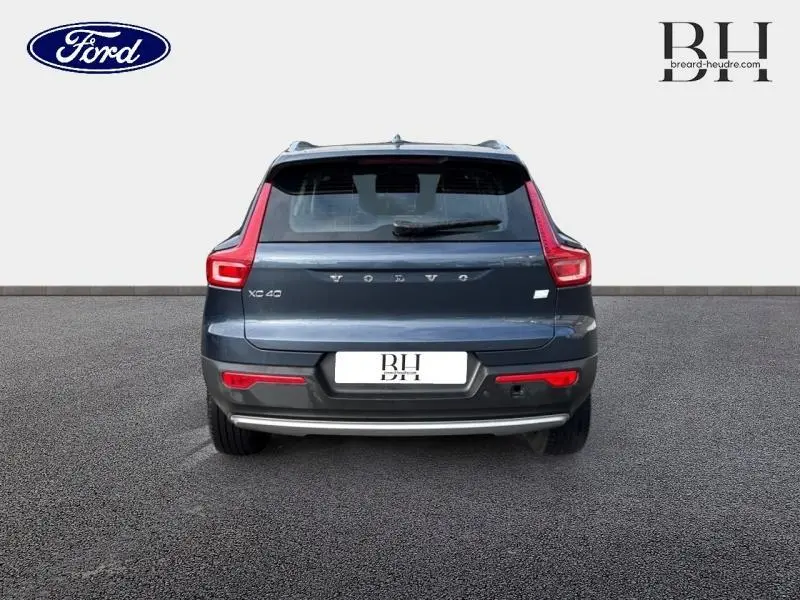 Vue arrière d'un Volvo XC40 bleu Denim avec feux LED verticaux et hayon fermé sur fond neutre.