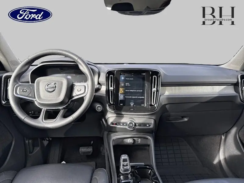 Vue intérieure du tableau de bord et volant noir d'un Volvo XC40 T4 Recharge 2021 avec écran tactile central et inserts bois.