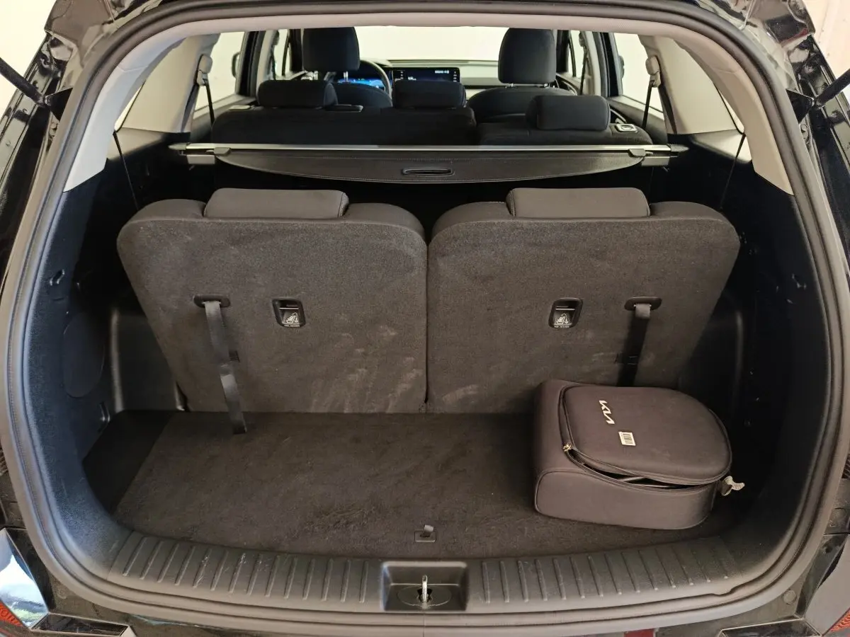 Coffre ouvert d’un KIA Sorento noir 2023, vue arrière, avec troisième rangée de sièges relevée et sac KIA noir posé.