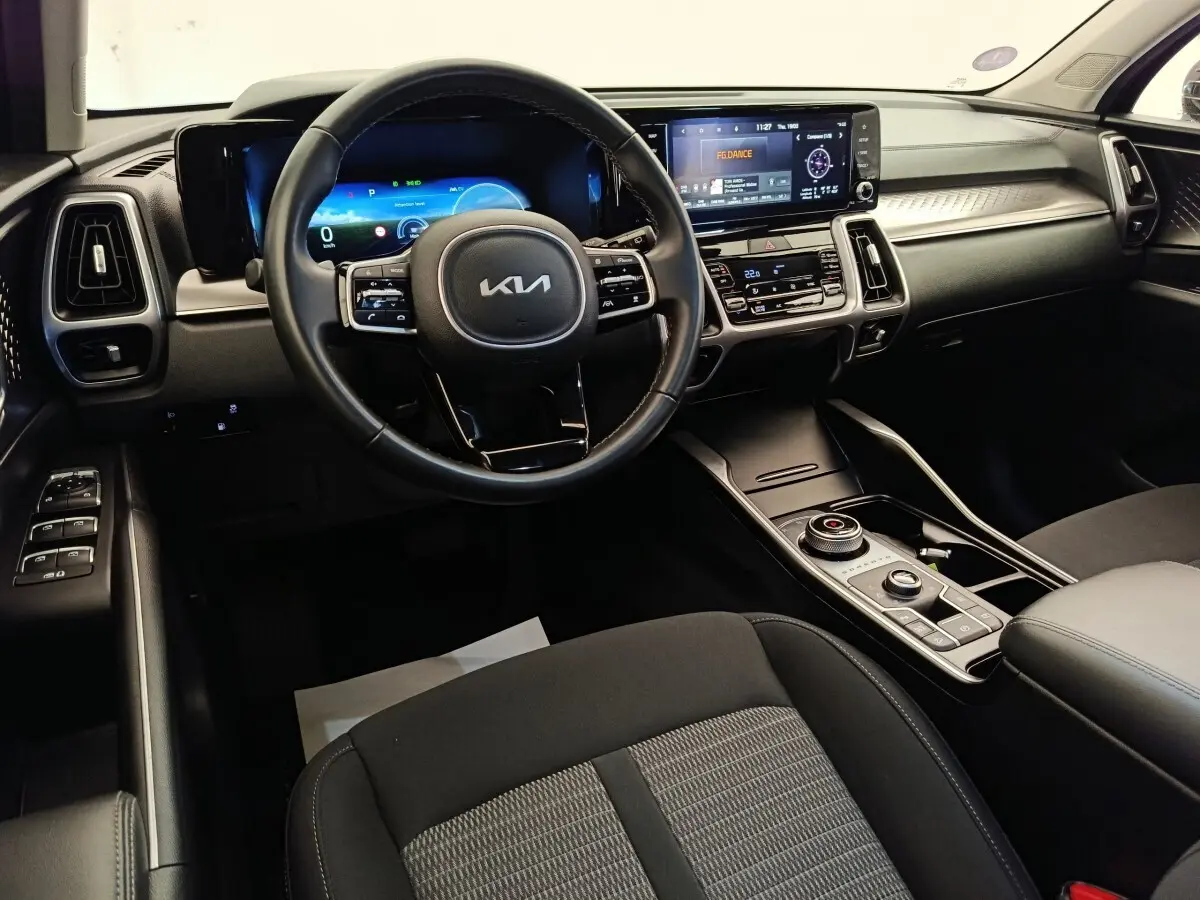 Vue intérieure avant du tableau de bord du Kia Sorento noir 2023 avec écran tactile et volant multifonctions en cuir.