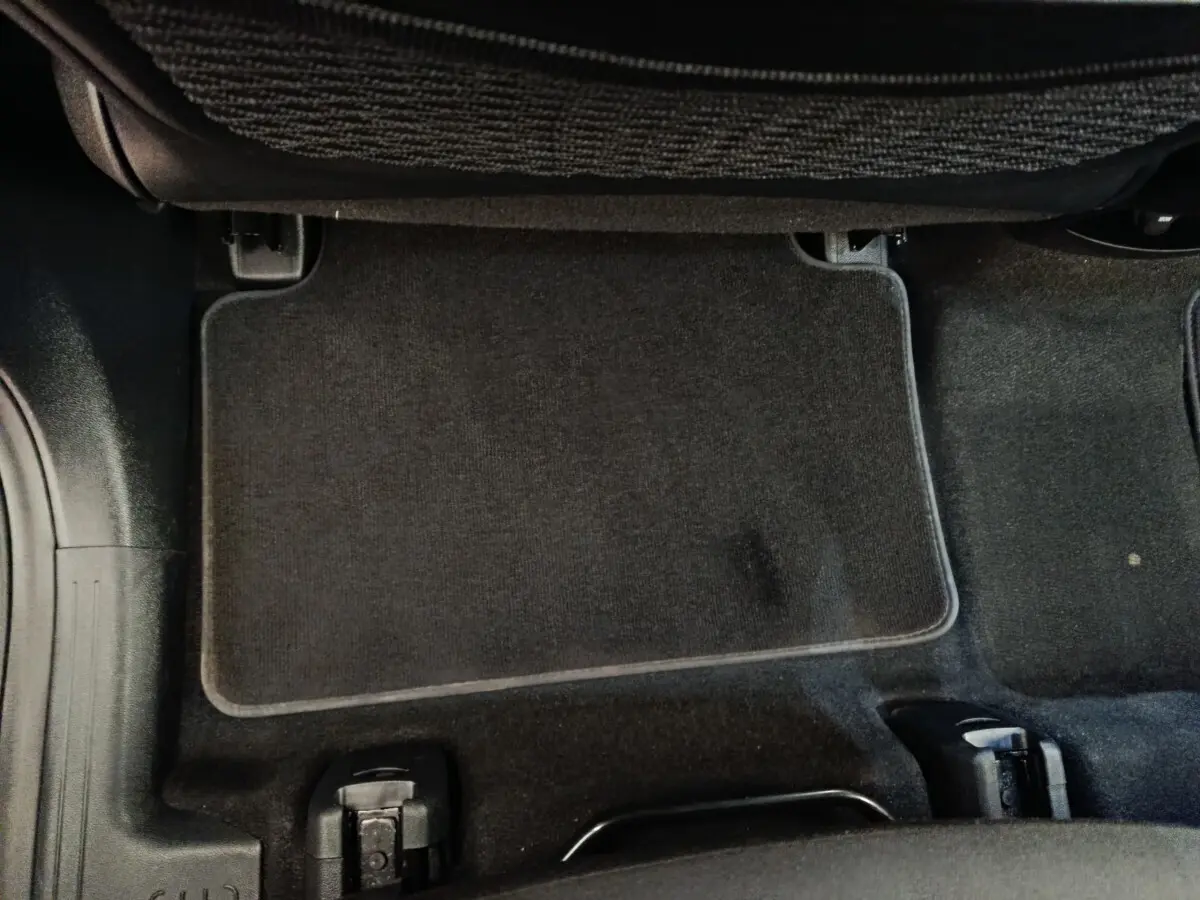 Vue rapprochée du tapis de sol noir sous le siège arrière d'un KIA Sorento 2023 hybride rechargeable.