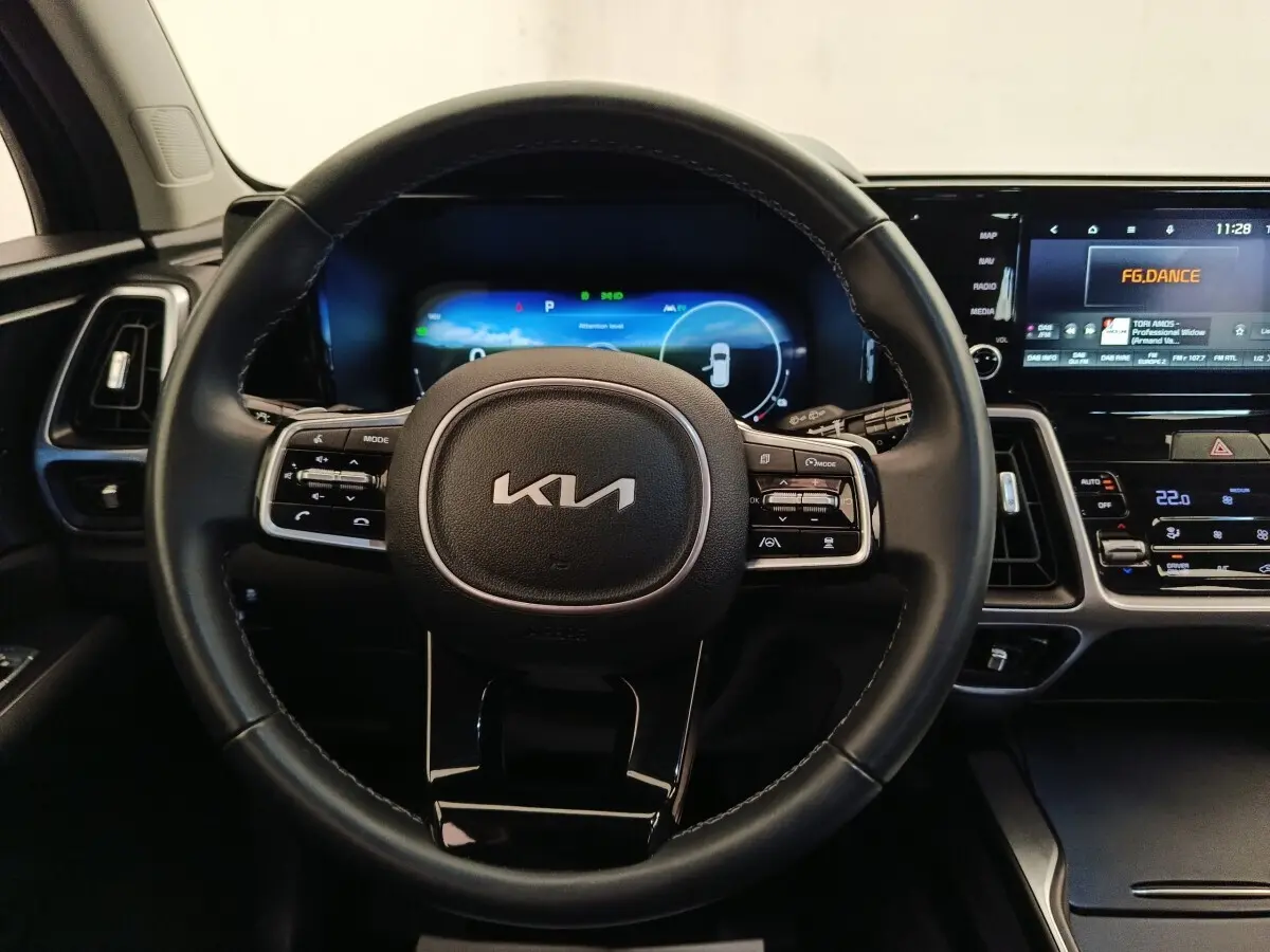 Vue intérieure centrée sur le volant noir du Kia Sorento 2023 avec tableau de bord digital et écran tactile.