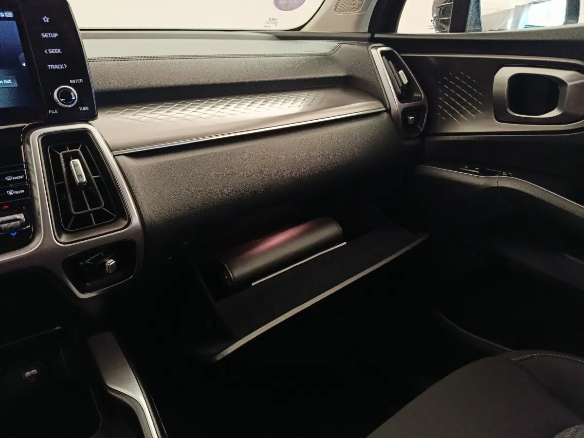 Intérieur KIA Sorento 2023 vue côté passager, tableau de bord noir avec boîte à gants ouverte et détails texturés.