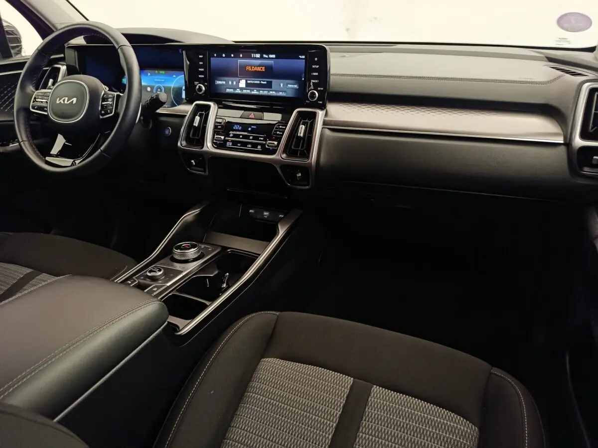 Vue intérieure du tableau de bord et console centrale du Kia Sorento 2023 hybride, avec écran tactile et volant cuir noir.
