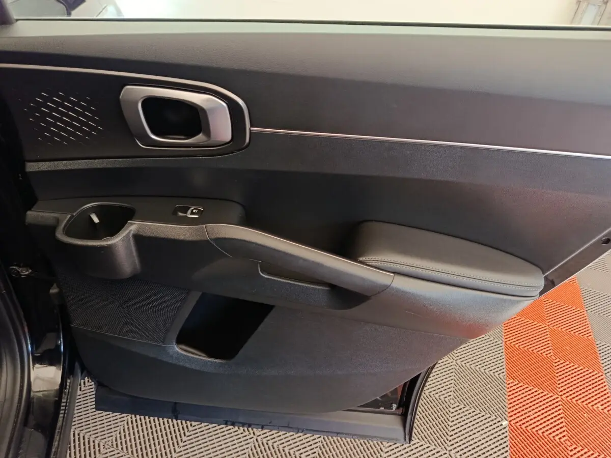 Vue intérieure du panneau de porte côté gauche noir du Kia Sorento 2023, avec accoudoir et poignée intégrée.