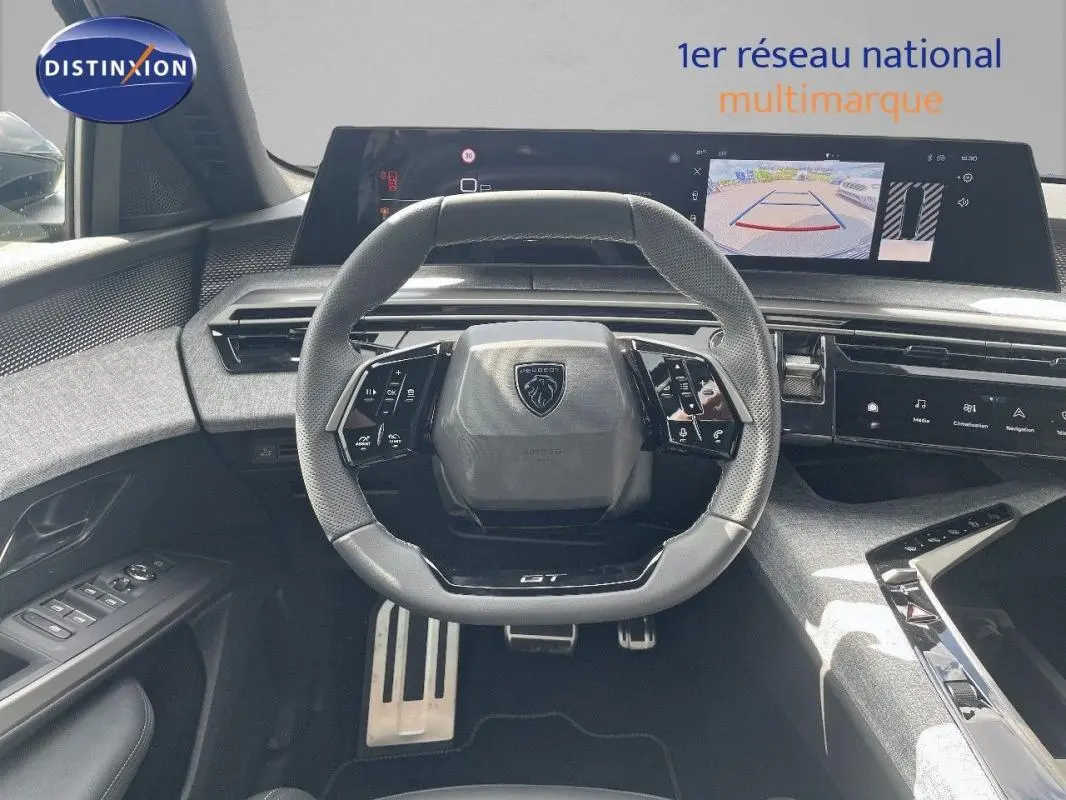 Vue intérieure centrée sur le volant cuir et le cockpit numérique du Peugeot 5008 noir, avec écran tactile et caméra de recul.