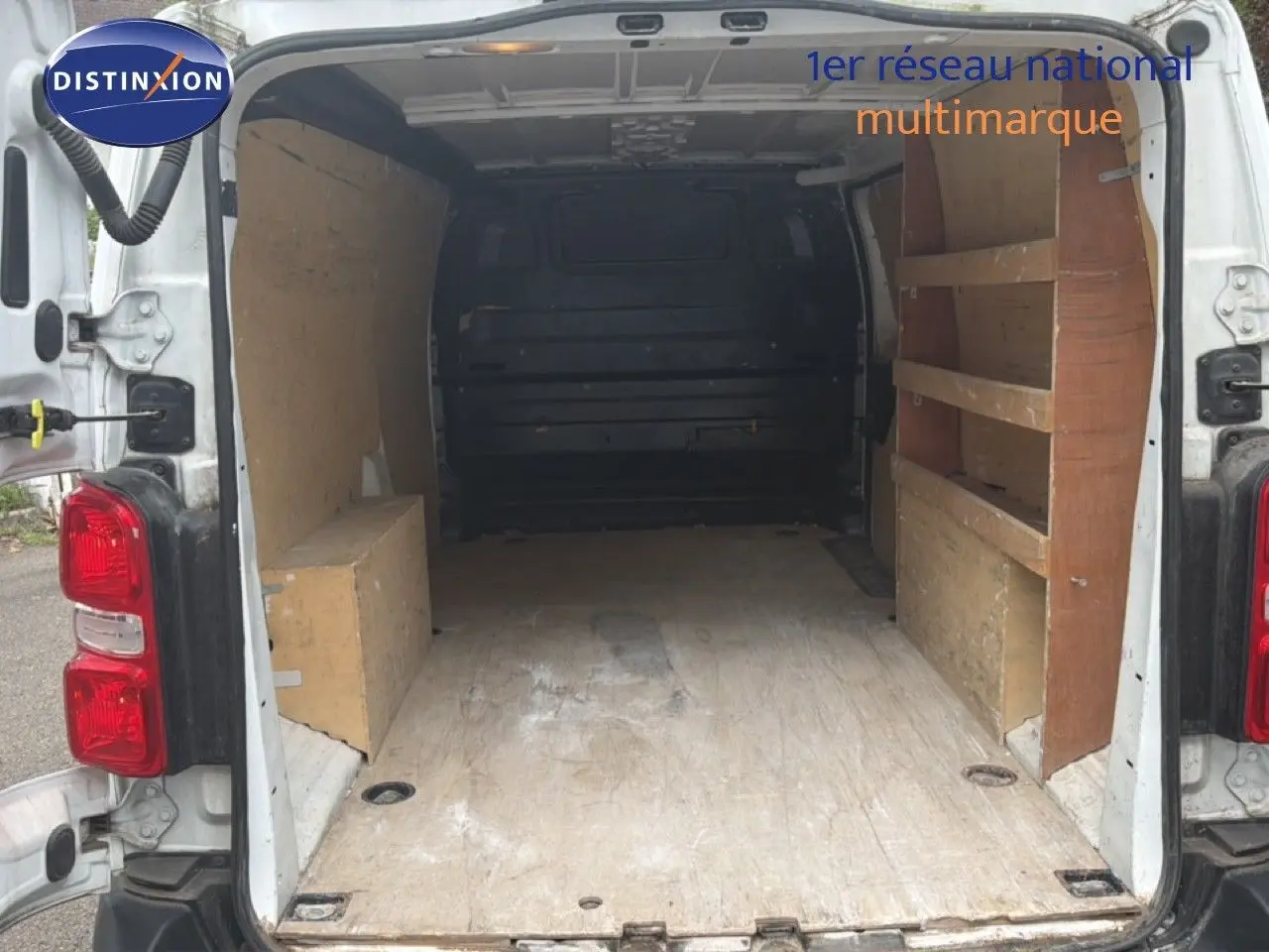Vue arrière du Citroën Jumpy XL blanc 2017 avec portes ouvertes montrant l’espace de chargement et étagères en bois.