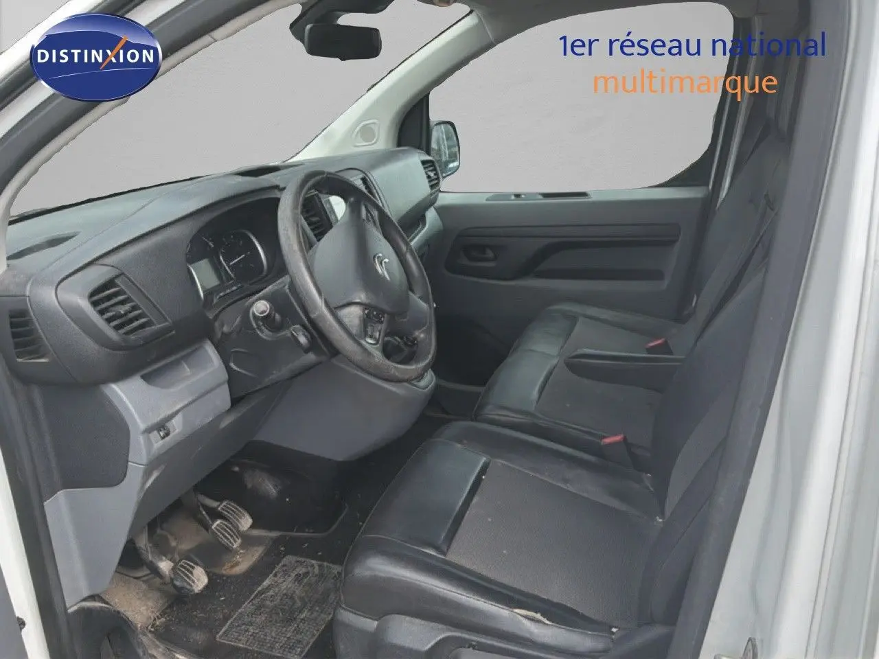 Vue intérieure côté conducteur du Citroën Jumpy blanc 2017, sièges en cuir noir et tableau de bord simple.