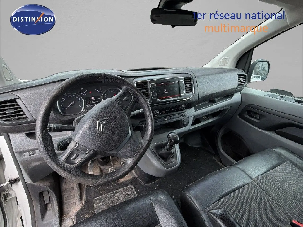 Vue intérieure côté conducteur du Citroën Jumpy blanc 2017, montrant le volant, tableau de bord et siège en cuir noir.