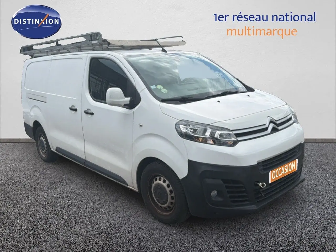 Vue 3/4 avant droit d’un Citroën Jumpy XL blanc avec galerie de toit et pare-chocs noir, en vente occasion.