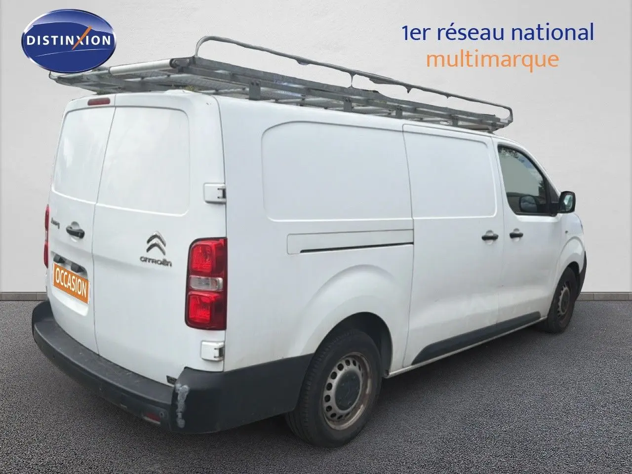 Vue 3/4 arrière droite d’un Citroën Jumpy XL blanc avec galerie de toit et pare-chocs arrière noir.