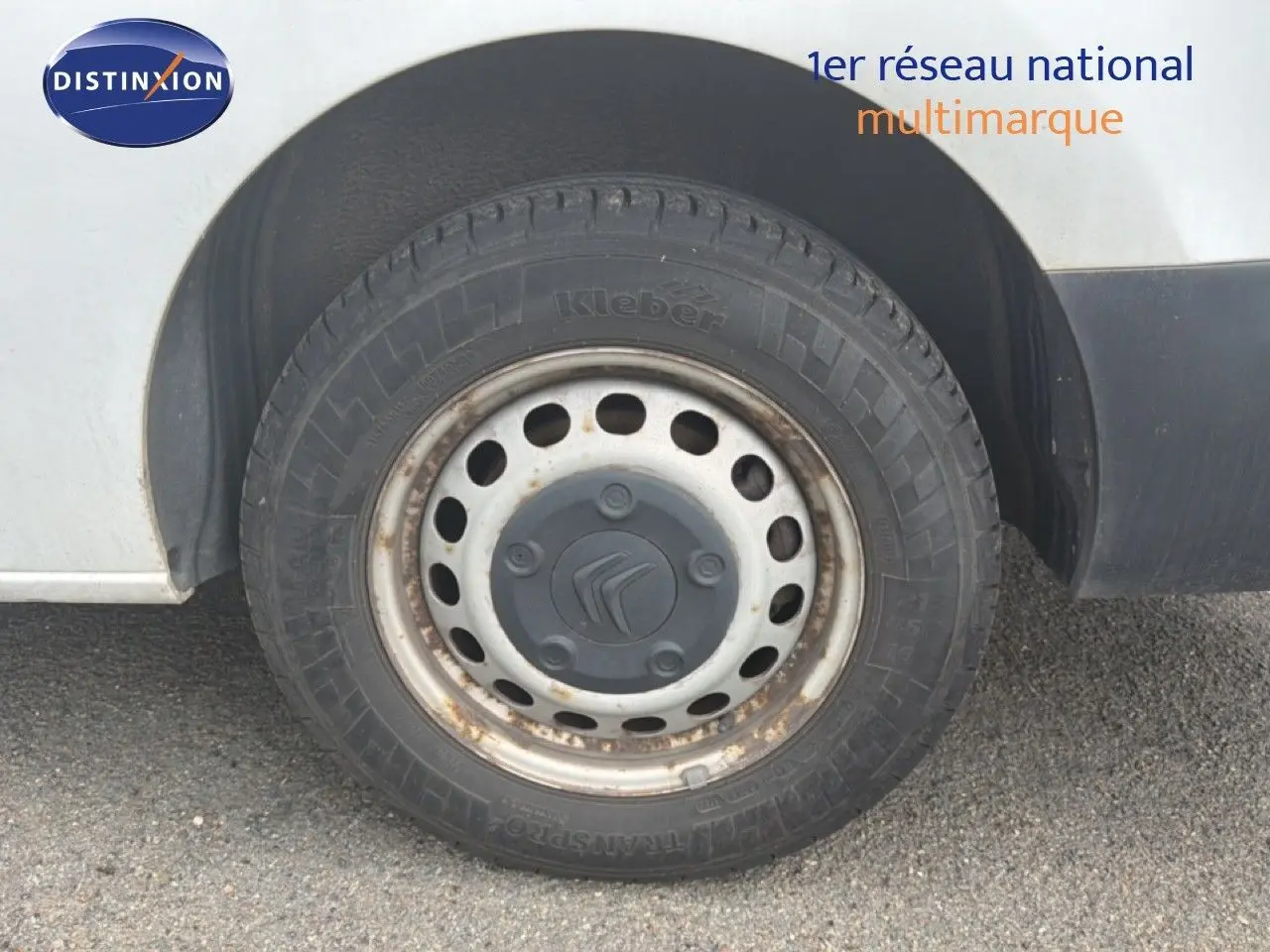 Gros plan sur la roue avant droite d’un Citroën Jumpy blanc, jante acier avec traces de rouille visibles.