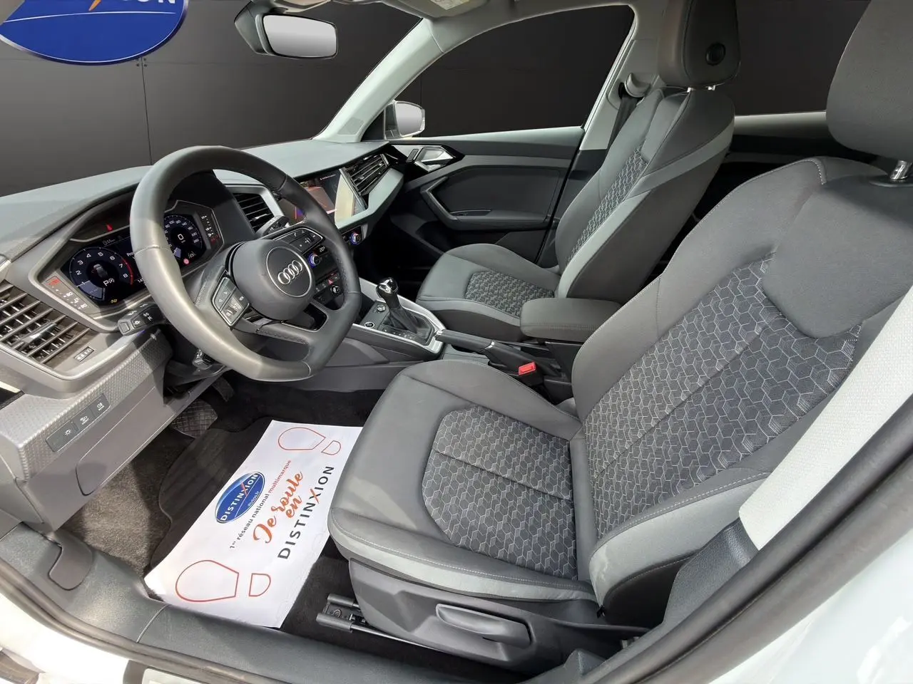 Vue intérieure côté conducteur de l'Audi A1 Sportback 2025 avec sièges tissu gris et tableau de bord moderne.
