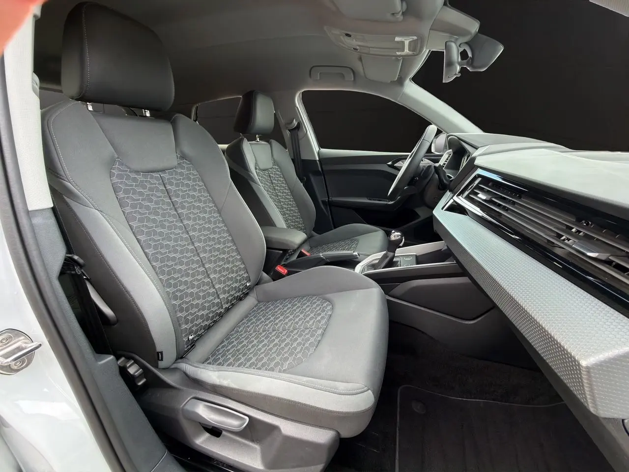 Vue intérieure côté conducteur de l'Audi A1 Sportback 2025 avec sièges gris et tableau de bord moderne.