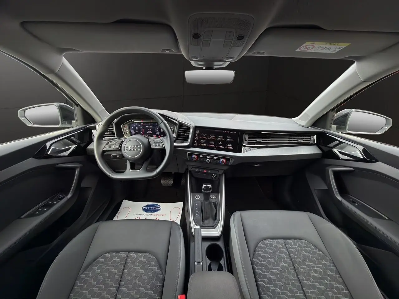 Vue intérieure avant de l'Audi A1 Sportback 2025 avec tableau de bord numérique et sièges noirs.