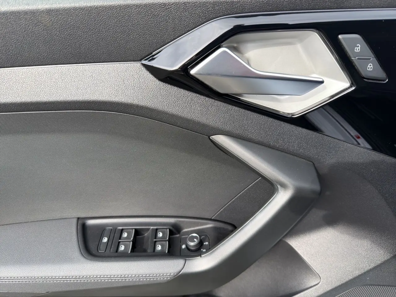 Détail de la porte intérieure côté conducteur de l'Audi A1 Sportback 2025 avec commandes de vitres et poignée argentée.