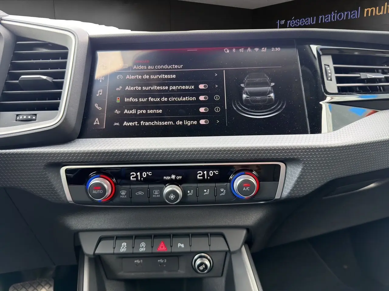 Vue rapprochée du tableau de bord de l'Audi A1 Sportback 2025 avec écran tactile et commandes de climatisation digitales.