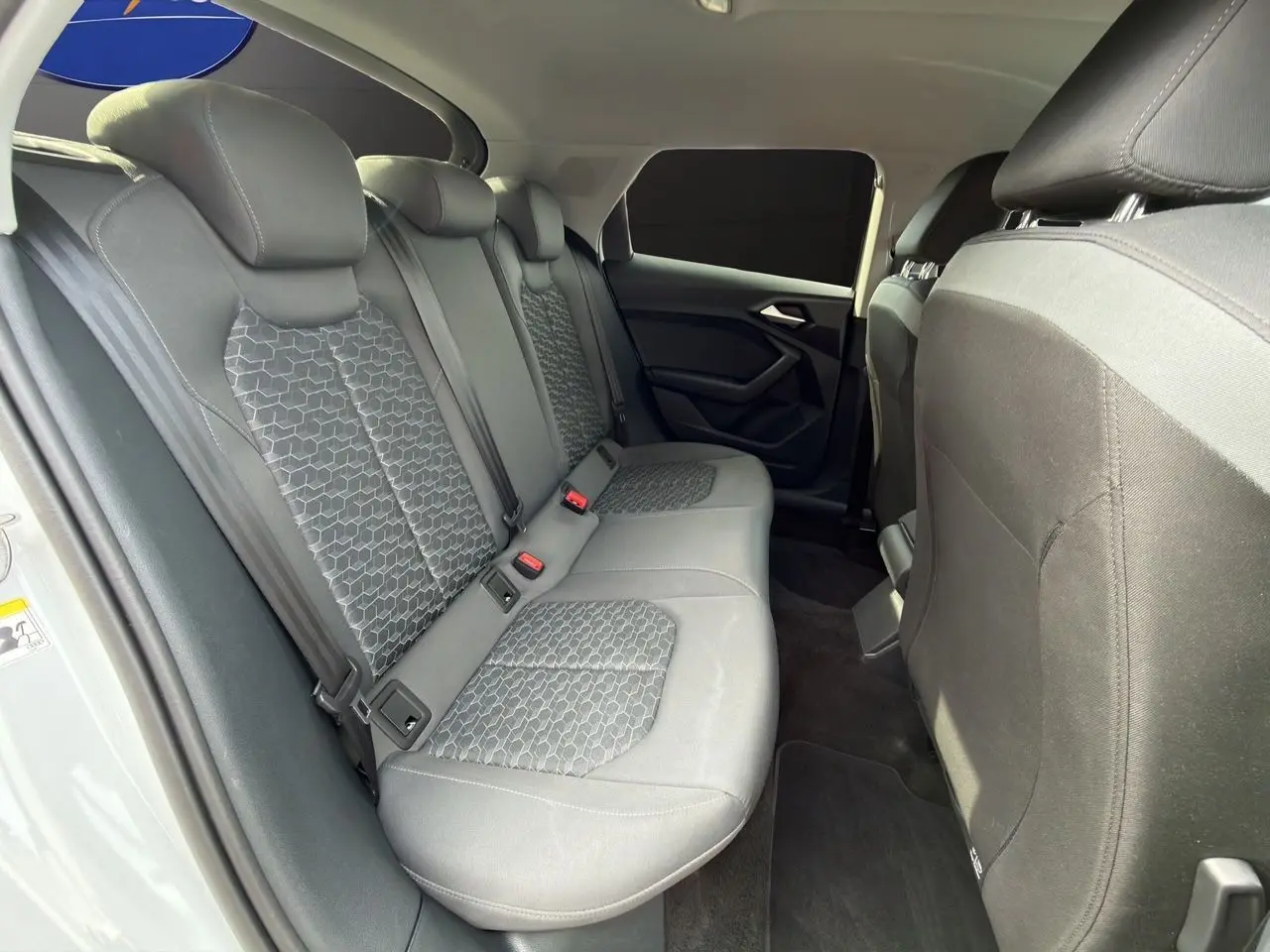 Vue intérieure côté gauche des sièges arrière gris à motifs hexagonaux de l'Audi A1 Sportback blanche 2025.