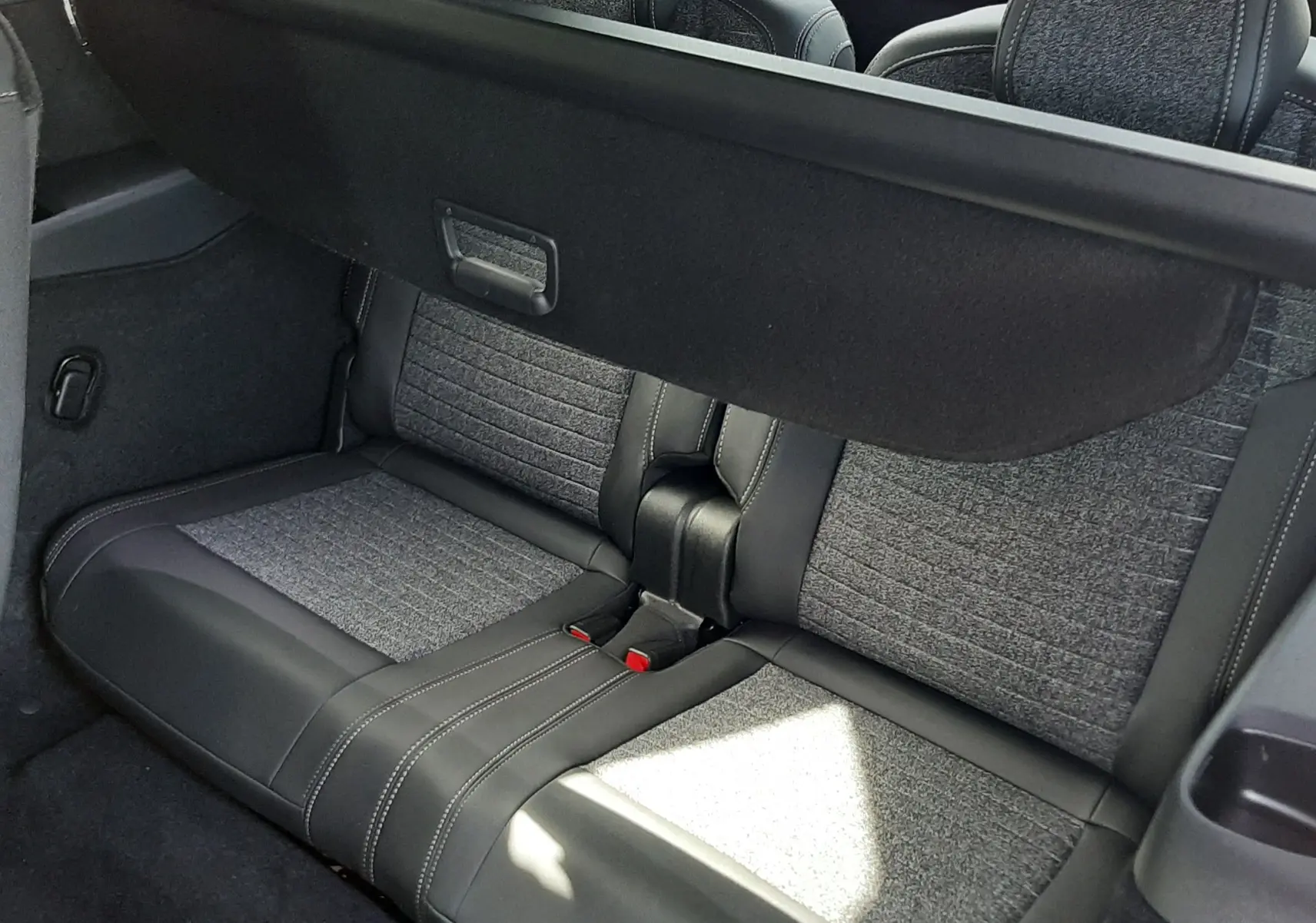 Vue intérieure arrière du Peugeot 5008 Hybrid 145ch Allure 2025, montrant les sièges gris tissu et cuir avec cache-bagages déployé.