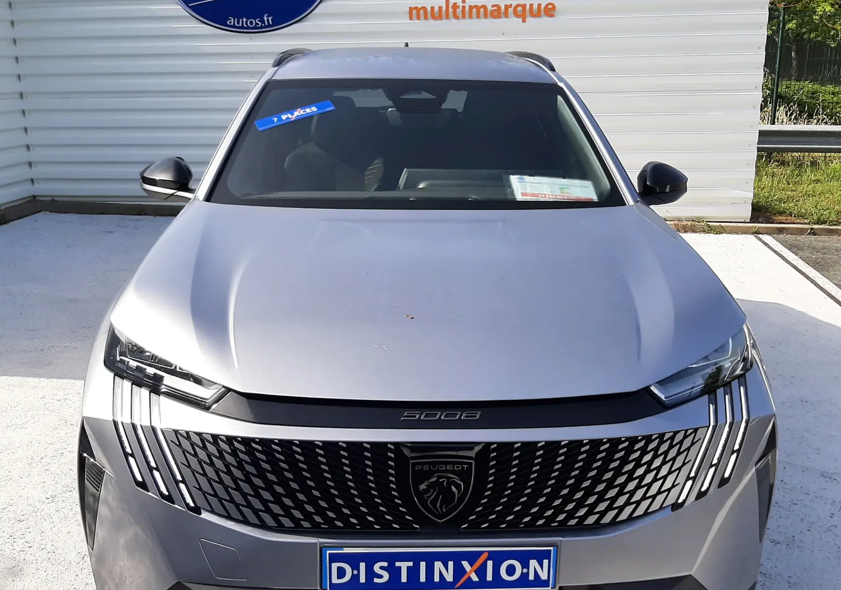 Vue avant d'un Peugeot 5008 gris Artense métal 2025 avec calandre noire distinctive et logo lion central.