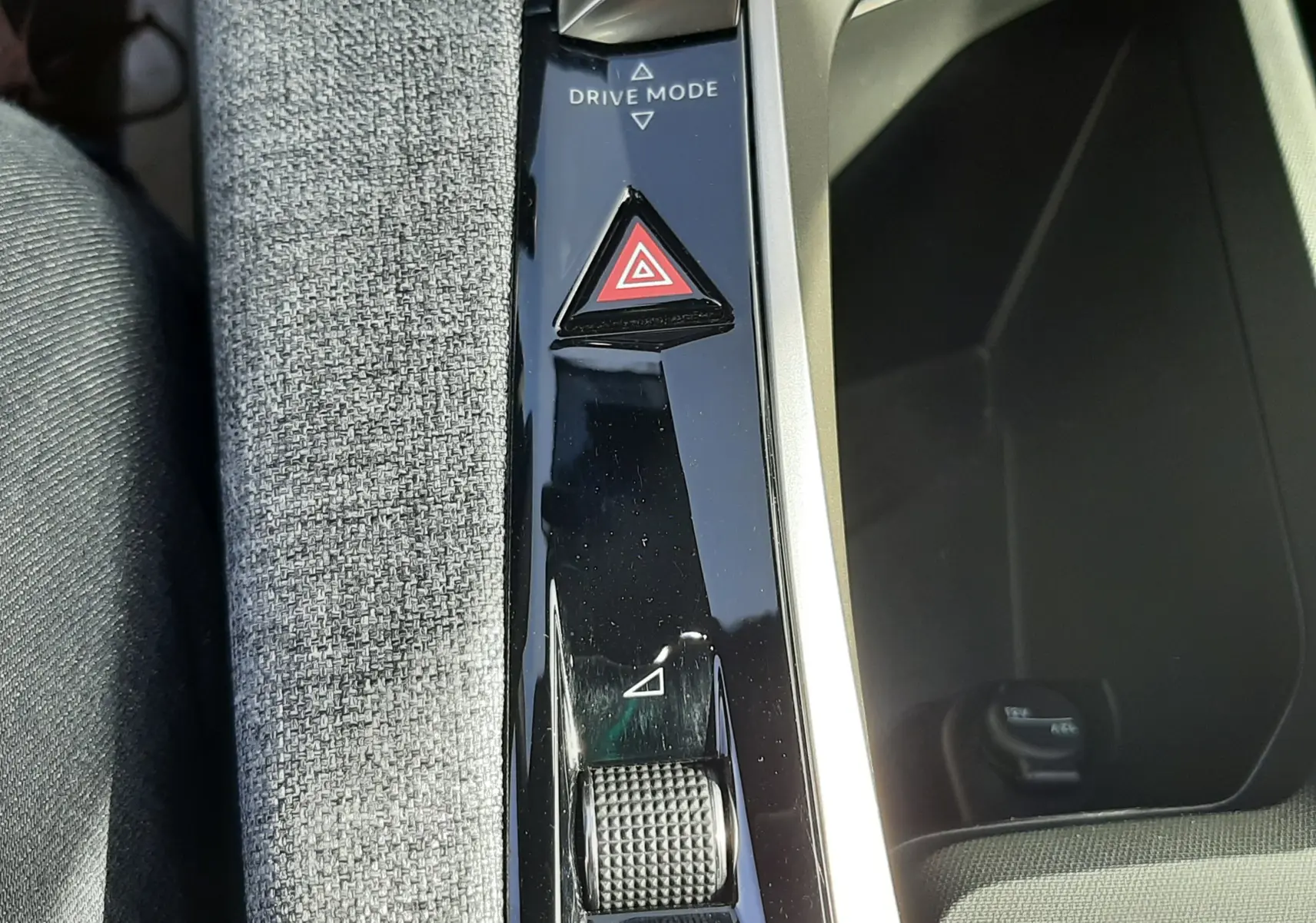 Gros plan sur la console centrale du Peugeot 5008 Hybrid 2025, avec bouton triangle rouge de signalisation et molette Drive Mode.