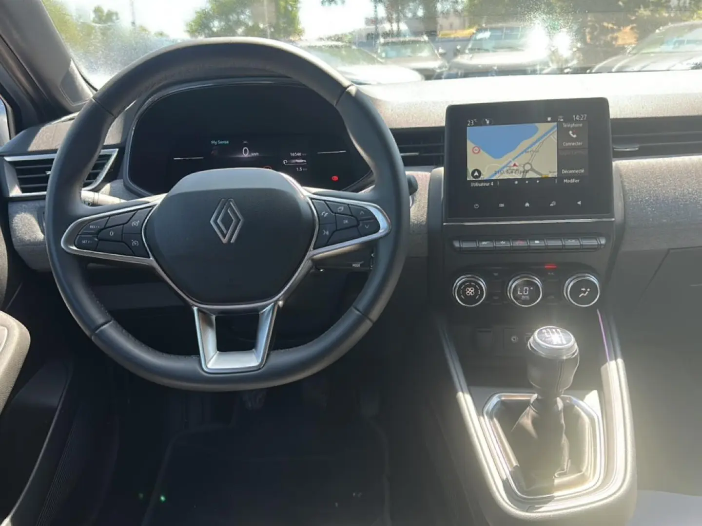 Vue intérieure centrée sur le volant Renault et la console centrale avec écran tactile et levier de vitesse manuel.