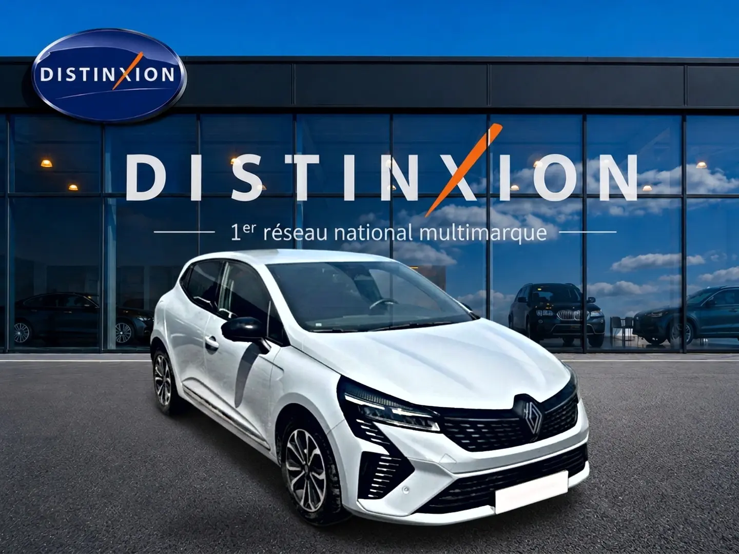 Renault Clio V gris rafale vue 3/4 avant droit, calandre noire et jantes alliage distinctives devant vitrine Distinxion.