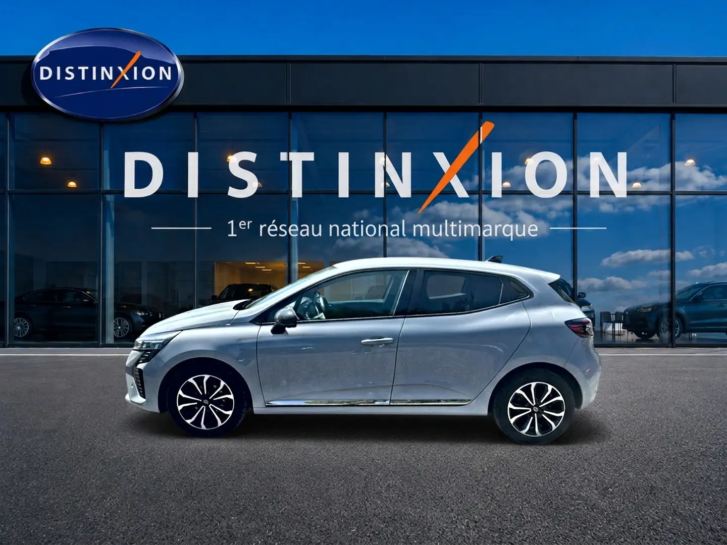 Renault Clio V gris rafale vue de profil côté gauche devant une vitrine avec logo Distinxion.