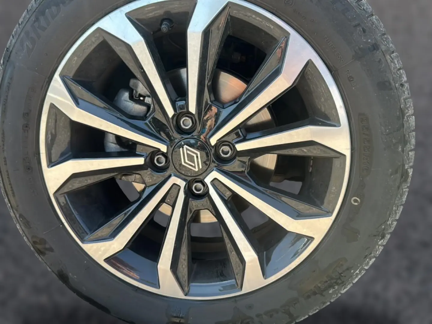 Gros plan sur la jante alu bicolore noir et argent avec logo Renault au centre, montée sur pneu Bridgestone.
