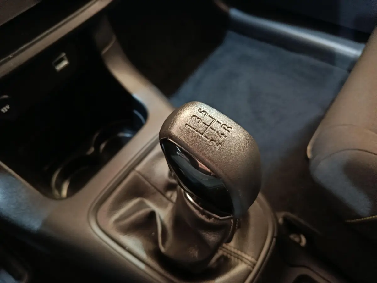 Gros plan sur le levier de vitesse manuel noir de la Citroën C3 PureTech 83 BVM PLUS, intérieur gris foncé.