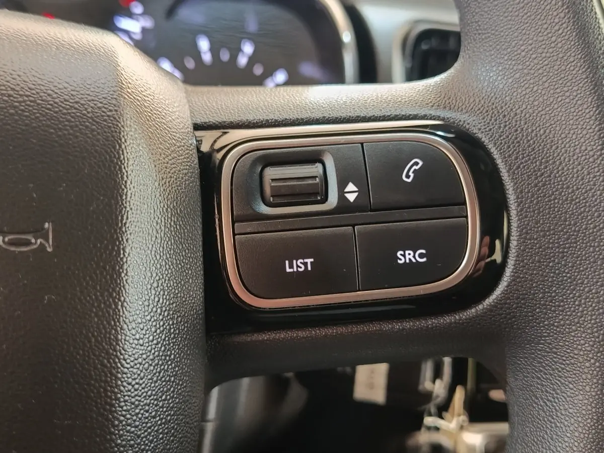 Gros plan sur les commandes gauche du volant noir de la Citroën C3 2024, boutons LIST, SRC et téléphone.