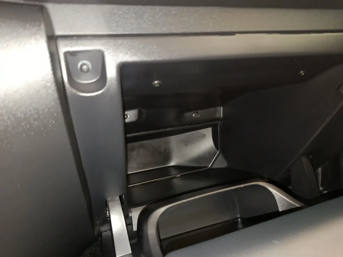 Vue rapprochée de la boîte à gants ouverte du Citroën C3 2024 gris foncé, montrant l'intérieur en plastique noir.